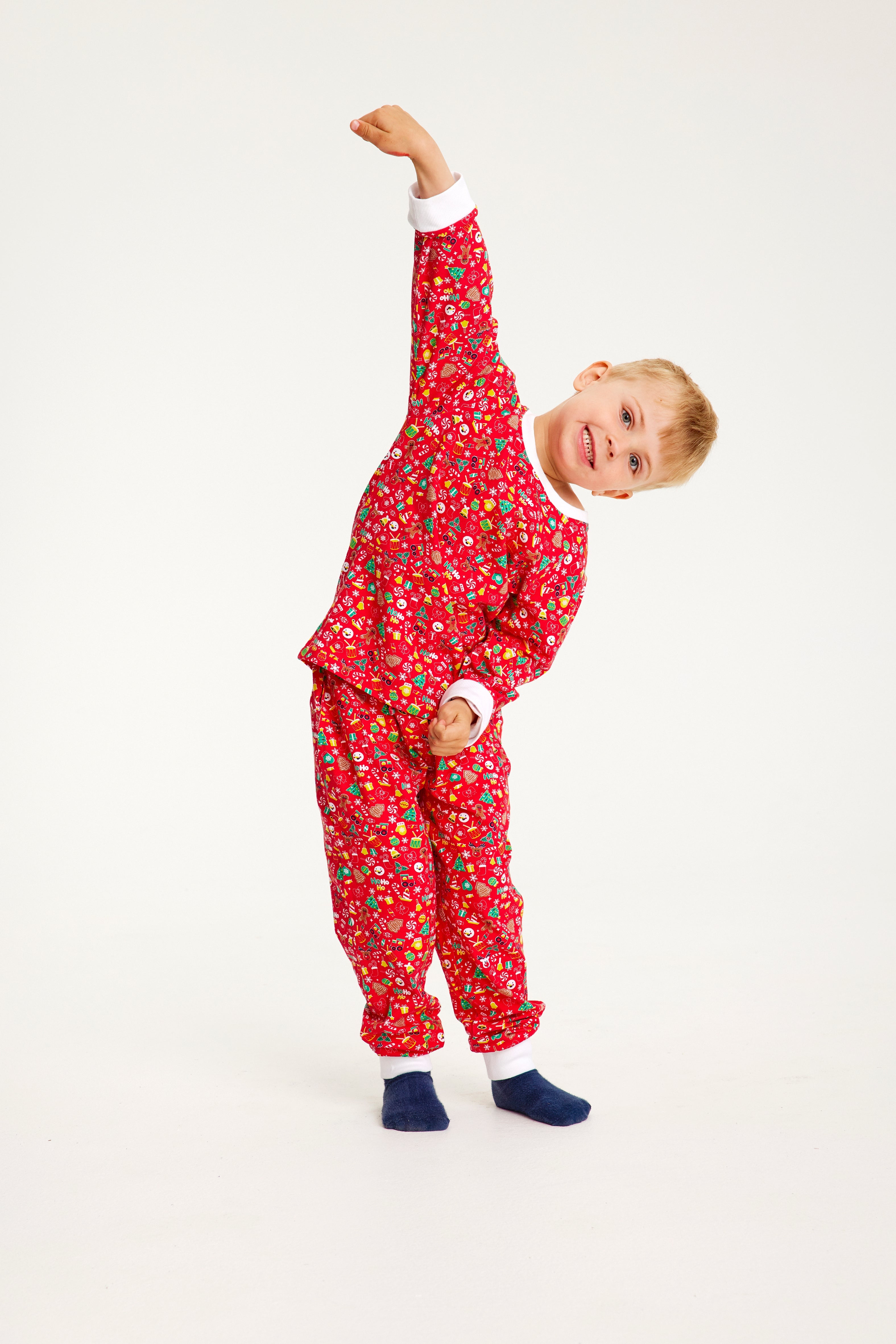 Et barn poserer i en postkasserød pyjamas med juletema.